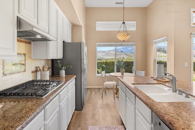 kitchen with dishwashing machine, under cabinet range hood, stainless steel gas cooktop, a sink, and white cabinetry