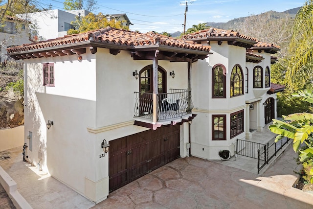 exterior space with a balcony, a tile roof, a patio, and stucco siding