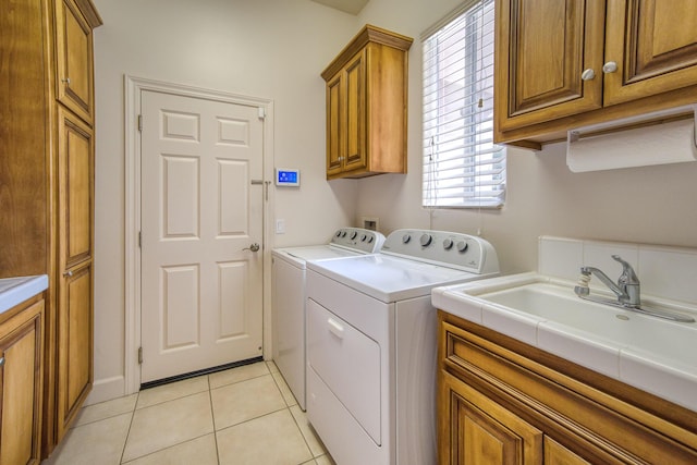 washroom featuring a sink, cabinet space, light tile patterned floors, and washer and dryer