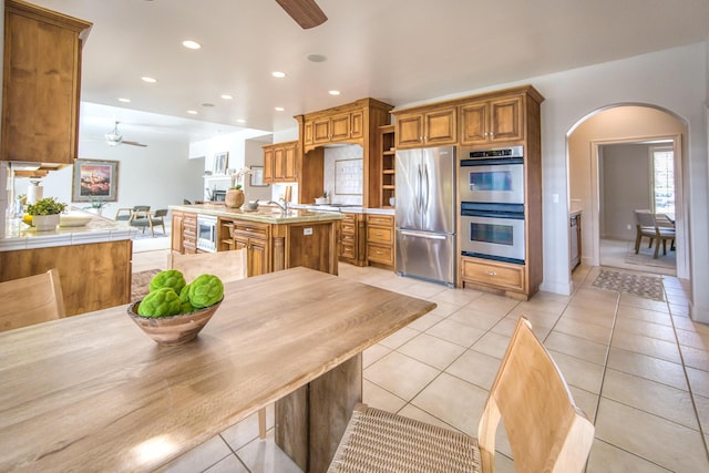 kitchen featuring open shelves, appliances with stainless steel finishes, a ceiling fan, and brown cabinets