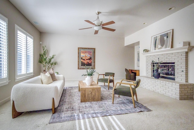 carpeted living area featuring visible vents, a fireplace, baseboards, and ceiling fan