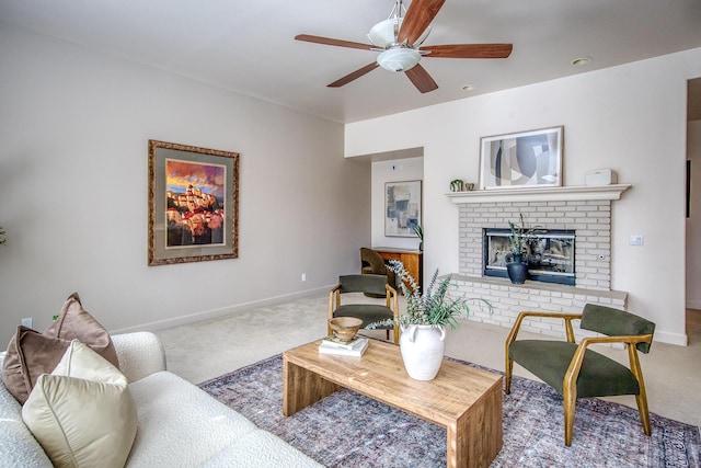 carpeted living room featuring a brick fireplace, ceiling fan, and baseboards