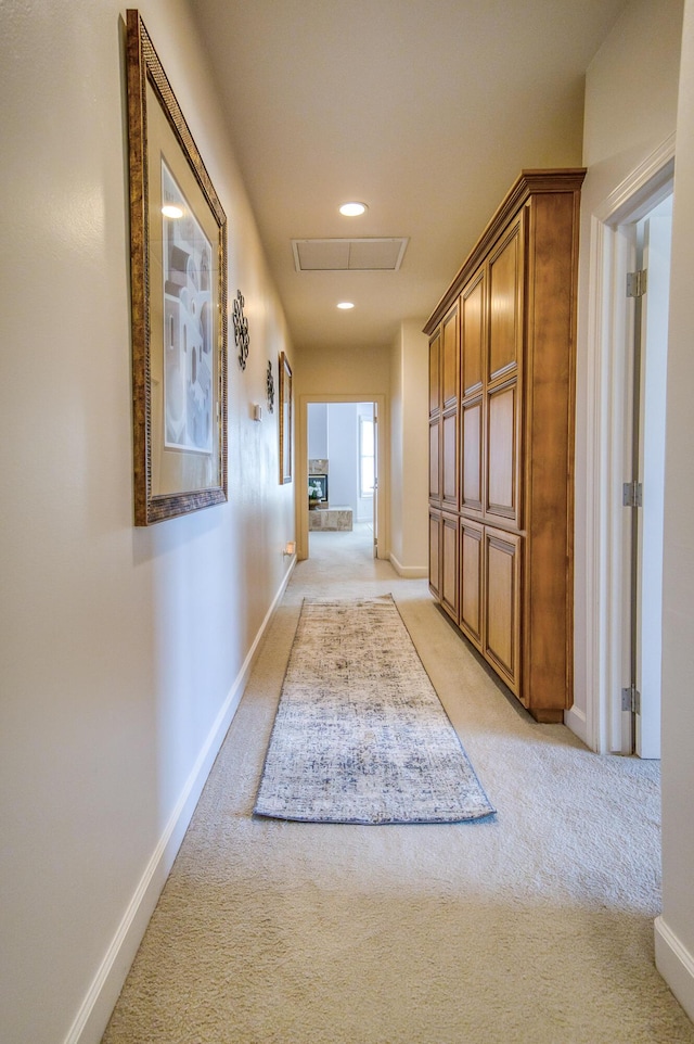 hallway with recessed lighting, light colored carpet, visible vents, and baseboards