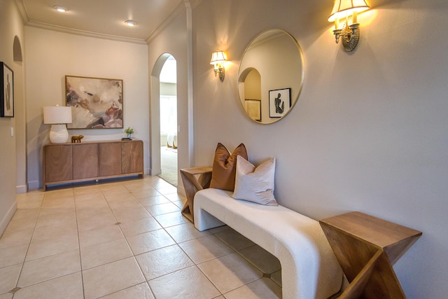 sitting room with light tile patterned floors, baseboards, arched walkways, and crown molding