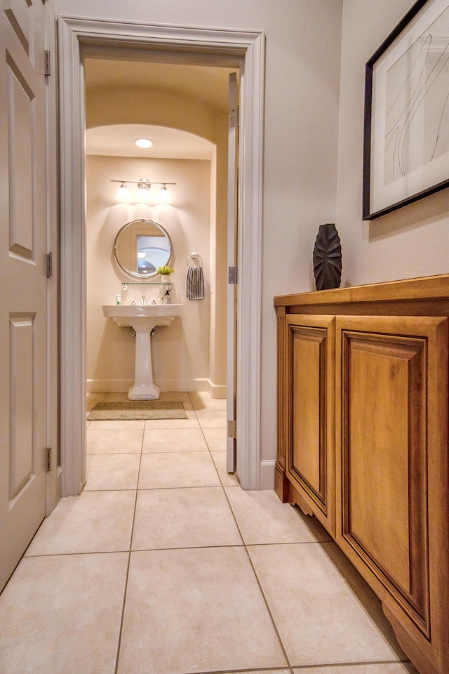 corridor featuring light tile patterned flooring and baseboards