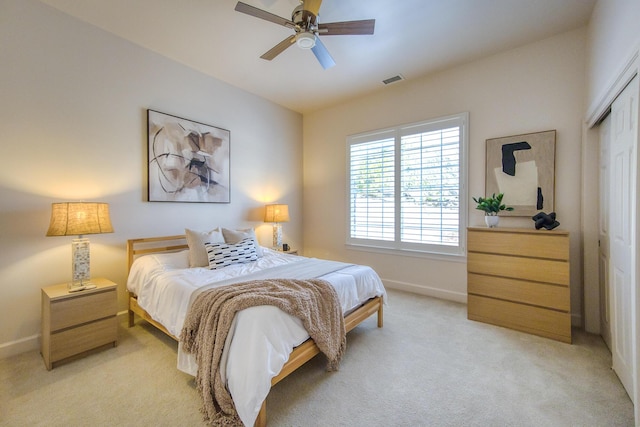 bedroom with visible vents, baseboards, light colored carpet, ceiling fan, and a closet