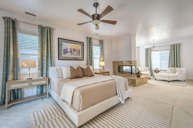 bedroom with a premium fireplace, multiple windows, carpet, and visible vents