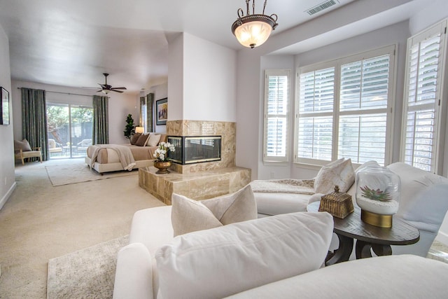 carpeted living area featuring a fireplace, visible vents, and a ceiling fan