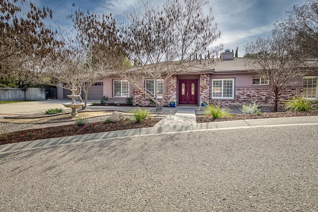 single story home featuring a chimney, stucco siding, concrete driveway, fence, and a garage