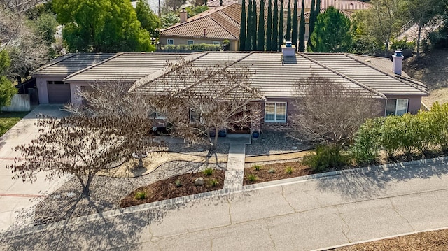 view of front of property featuring a garage, driveway, a chimney, and a tile roof