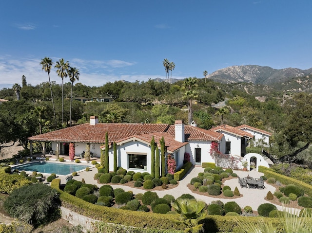 exterior space with an outdoor pool, a chimney, a tiled roof, a patio area, and stucco siding