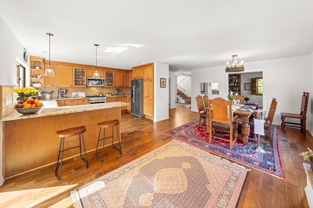 dining area featuring an inviting chandelier, stairs, and dark wood-style flooring