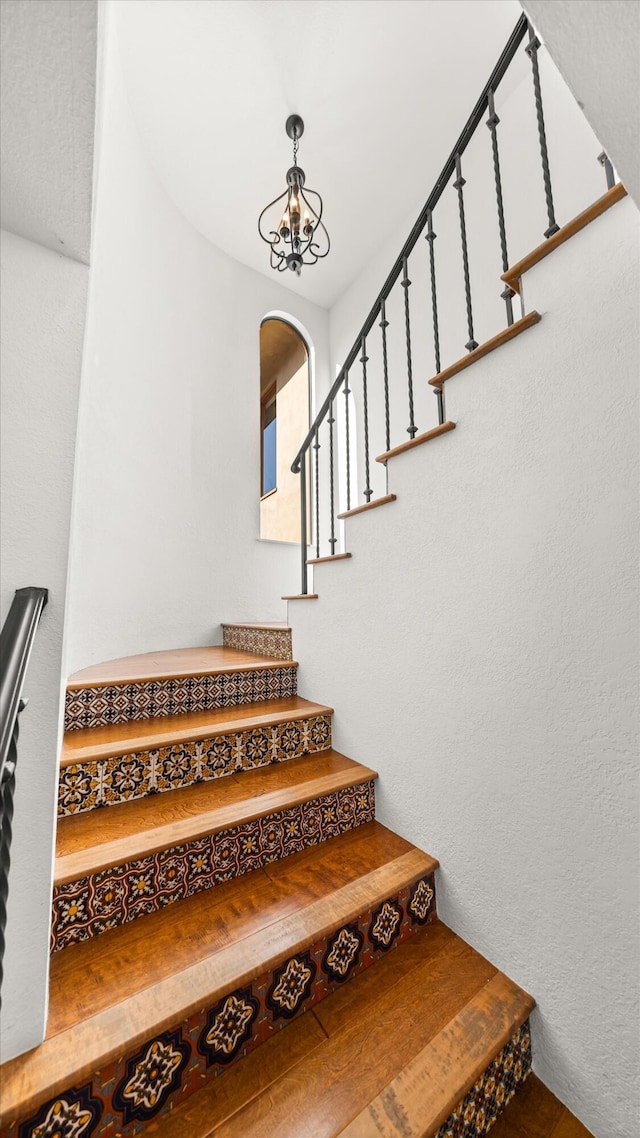 stairs featuring arched walkways and a notable chandelier