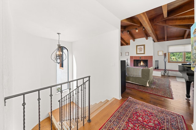 corridor featuring a notable chandelier, lofted ceiling with beams, hardwood / wood-style floors, an upstairs landing, and wood ceiling