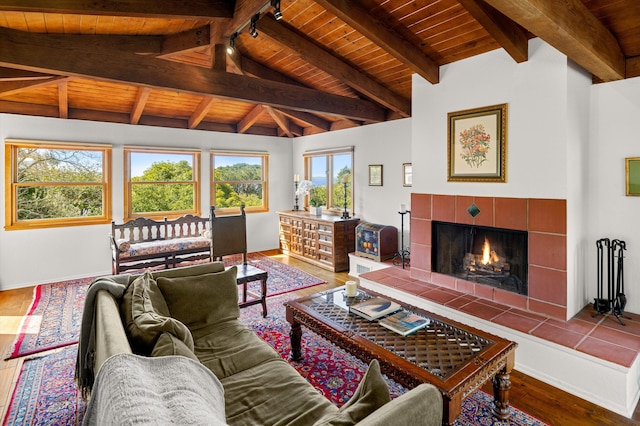 living area with wood ceiling, a tiled fireplace, wood finished floors, baseboards, and lofted ceiling with beams