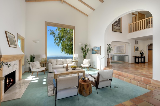 carpeted living area with high vaulted ceiling, a premium fireplace, and beam ceiling