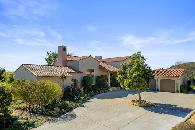 mediterranean / spanish house with concrete driveway, an attached garage, a tiled roof, and stucco siding