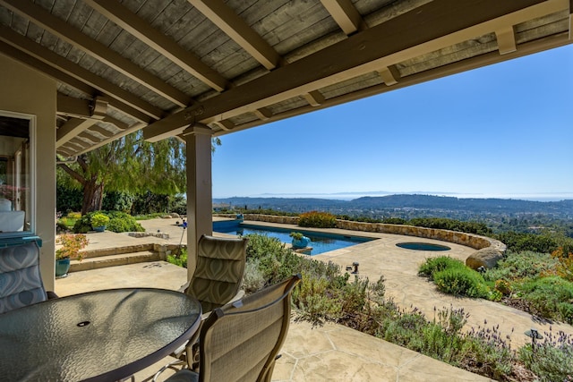 view of patio featuring outdoor dining space, a mountain view, an outdoor pool, and a jacuzzi