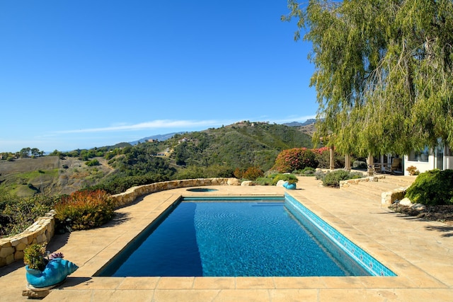 pool with a patio, a jacuzzi, and a mountain view