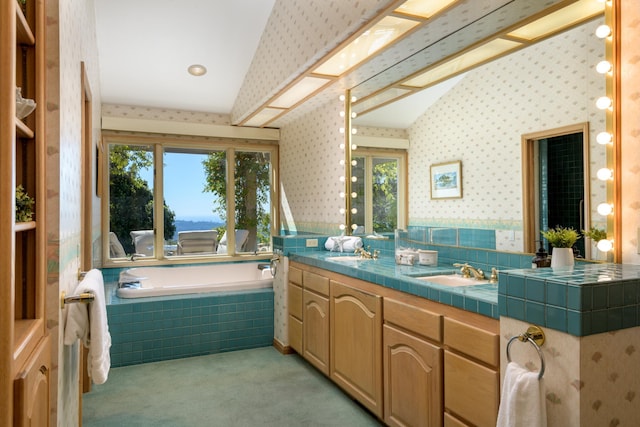 bathroom featuring double vanity, lofted ceiling, a sink, tiled tub, and wallpapered walls