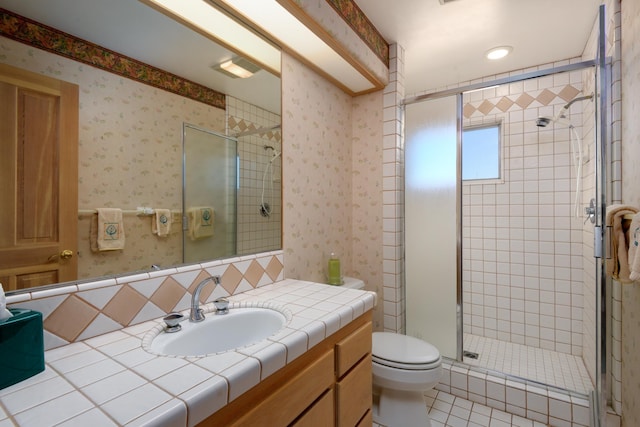 full bathroom featuring wallpapered walls, a stall shower, toilet, tile patterned flooring, and vanity