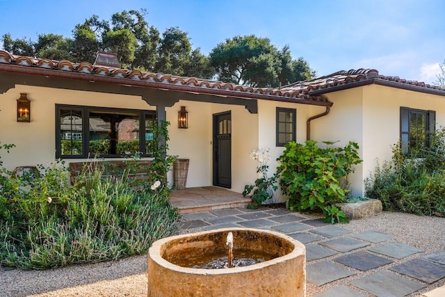 doorway to property with a tile roof and stucco siding