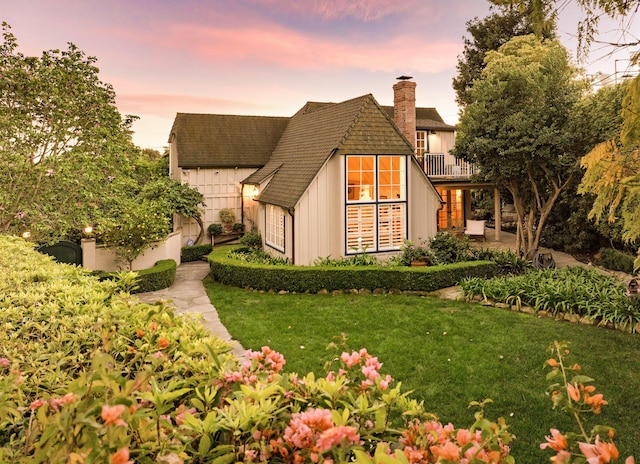 view of front of house with a front lawn, a chimney, a patio area, and a balcony