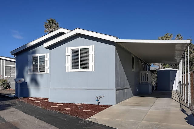 view of home's exterior featuring concrete driveway, crawl space, a shed, an attached carport, and an outdoor structure