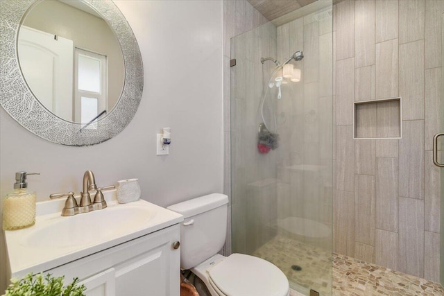 full bath with tiled shower, vanity, and toilet