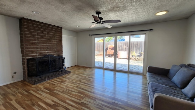 unfurnished living room featuring baseboards, a ceiling fan, wood finished floors, a textured ceiling, and a fireplace