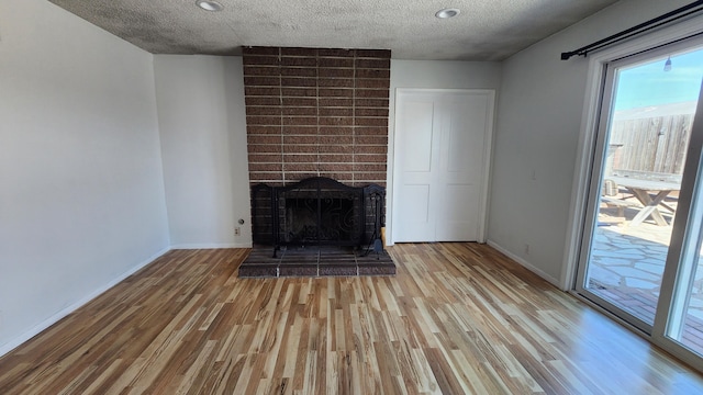 unfurnished living room with a fireplace, wood finished floors, and a healthy amount of sunlight