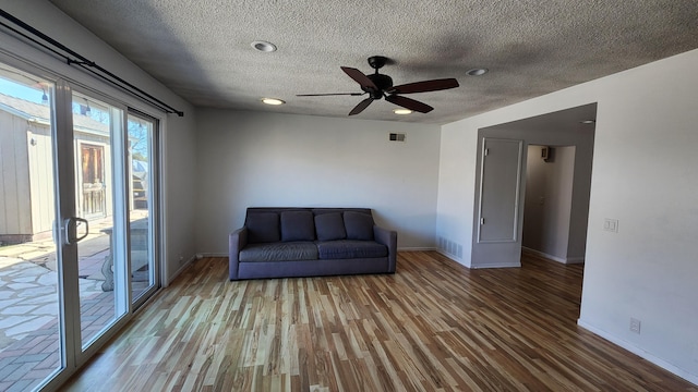 unfurnished room with visible vents, a textured ceiling, baseboards, and wood finished floors