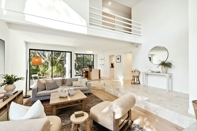 living area with visible vents, a high ceiling, and marble finish floor