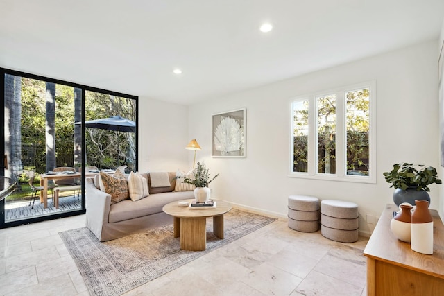 living room featuring floor to ceiling windows, recessed lighting, a healthy amount of sunlight, and baseboards