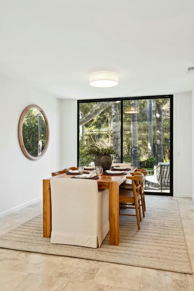 dining room with a healthy amount of sunlight, a wall of windows, and baseboards