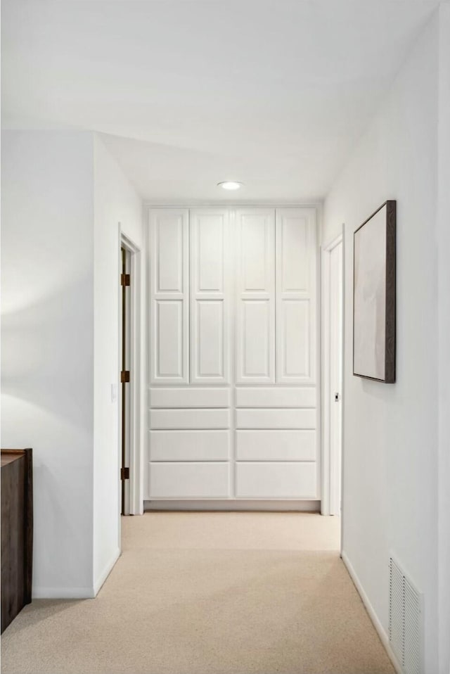 hallway with visible vents, baseboards, and carpet