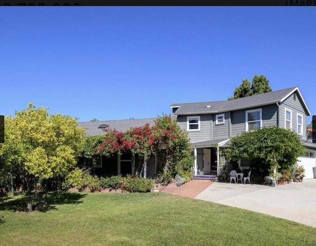 view of front of home featuring concrete driveway, a front lawn, and a patio area