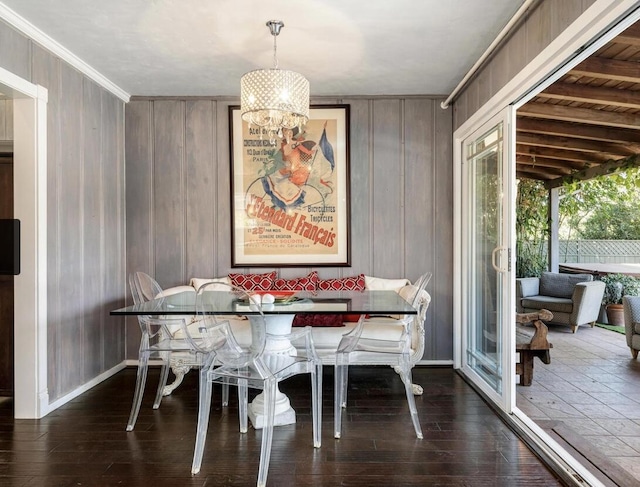 dining area featuring wooden walls, baseboards, breakfast area, wood finished floors, and a notable chandelier