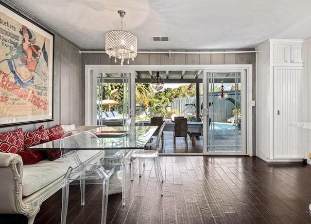 unfurnished dining area with an inviting chandelier, visible vents, wood finished floors, and ornamental molding