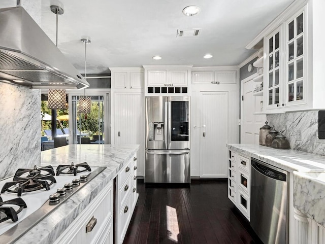 kitchen with range hood, appliances with stainless steel finishes, glass insert cabinets, white cabinetry, and light stone countertops