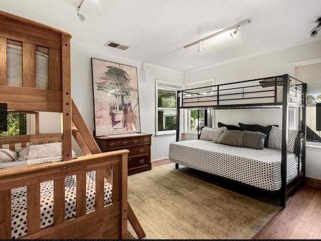 bedroom featuring rail lighting, visible vents, and wood finished floors