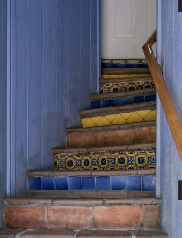 stairway featuring wood walls