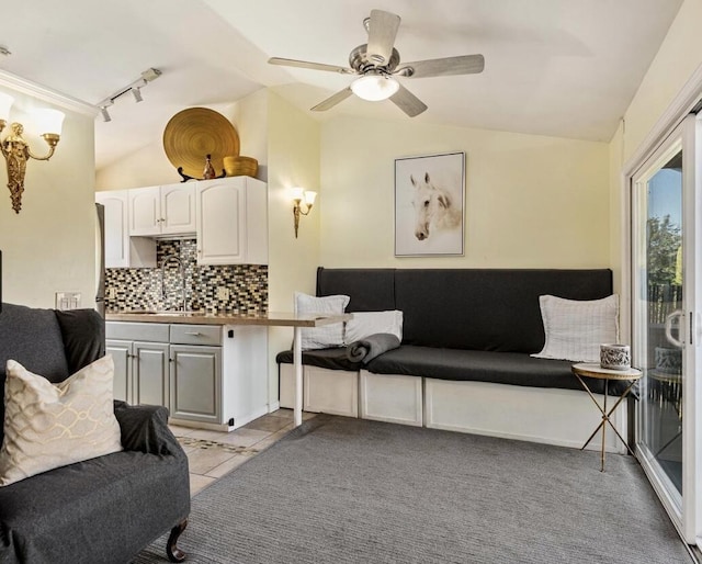 living room featuring lofted ceiling, rail lighting, light tile patterned flooring, ceiling fan, and light carpet