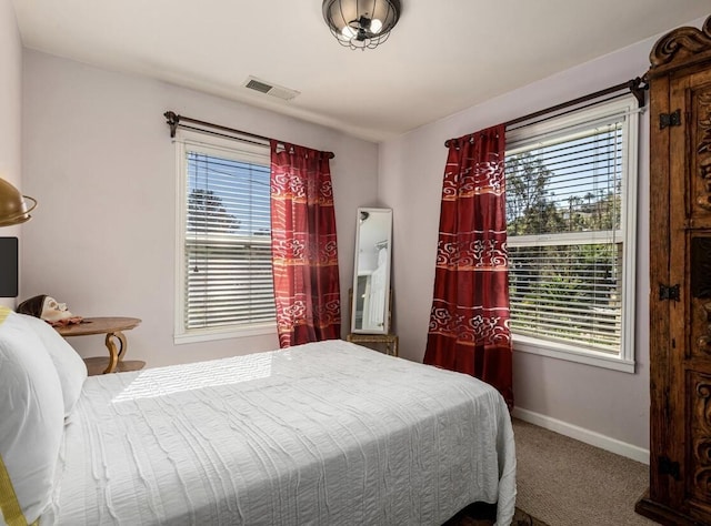 carpeted bedroom featuring baseboards, multiple windows, and visible vents