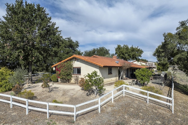 view of front of house with a tile roof, fence, a chimney, and stucco siding