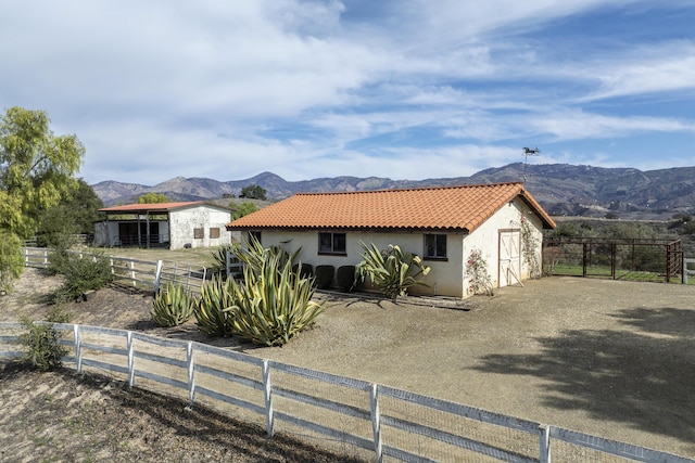 view of front of property featuring a tile roof, a mountain view, fence, and stucco siding