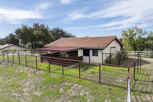 exterior space featuring an outbuilding, a tile roof, an exterior structure, and stucco siding