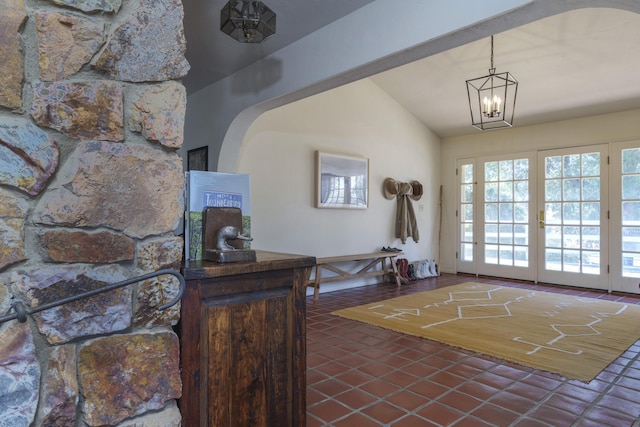 entryway featuring lofted ceiling, dark tile patterned flooring, and an inviting chandelier