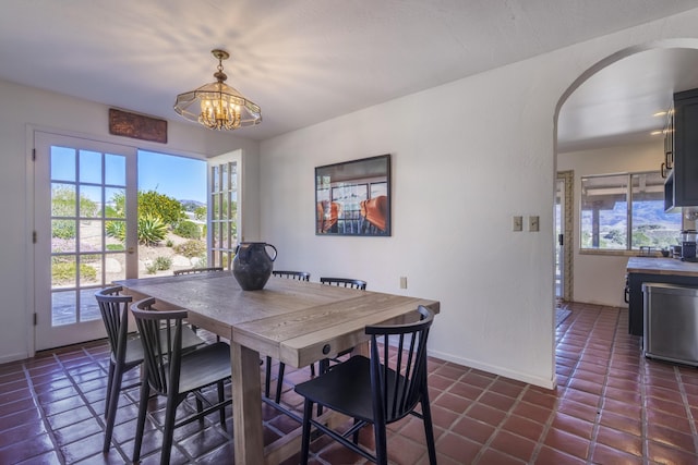 dining space featuring baseboards, a chandelier, and arched walkways