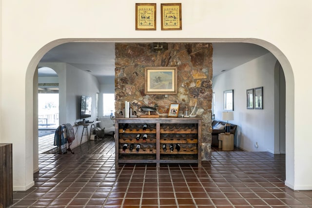 interior space with tile patterned flooring, arched walkways, and baseboards